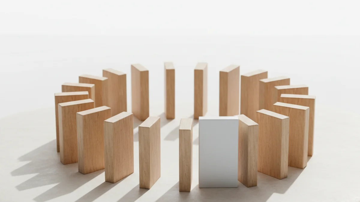 Fileira de dominós de madeira em curva sobre superfície de pedra, uma peça virada para cima.