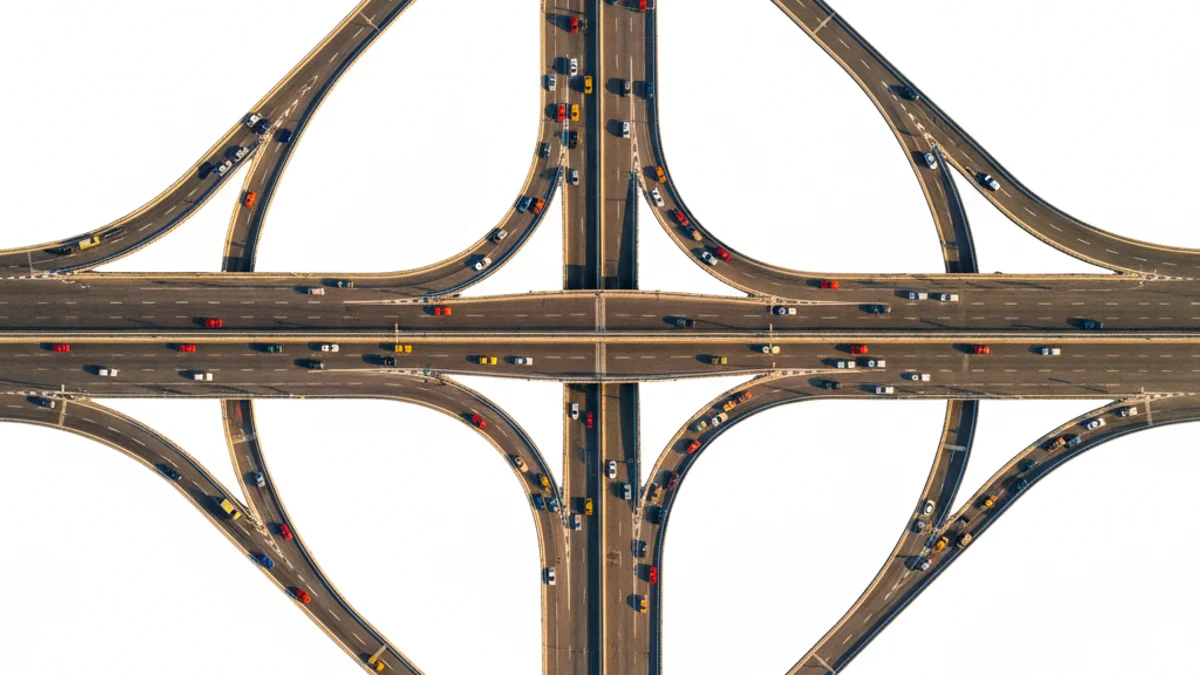 Vista aérea de entroncamento urbano com múltiplas vias convergindo em uma única artéria.