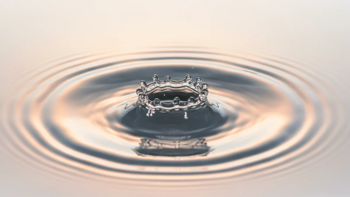 Gota d'água criando ondas concêntricas ao tocar superfície, metáfora de responsividade.
