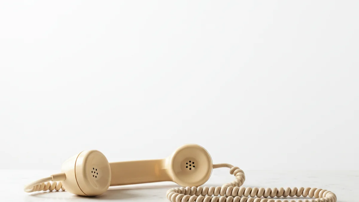 Telefone bakelite vintage fora do gancho sobre superfície de mármore branco.