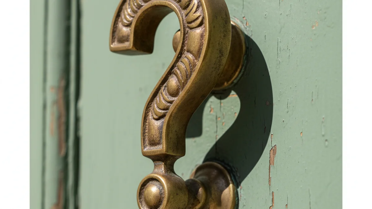 Aldrava de latão em formato de ponto de interrogação em porta verde desgastada.