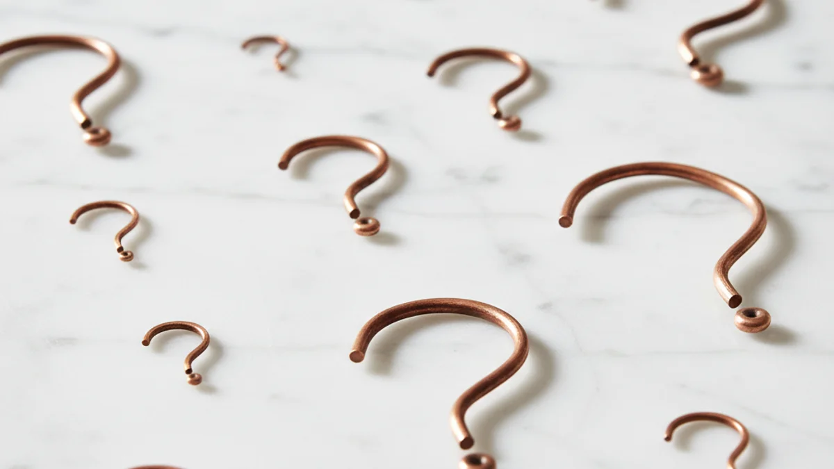 Marcas de interrogação feitas de arame de cobre espalhadas sobre mármore branco.