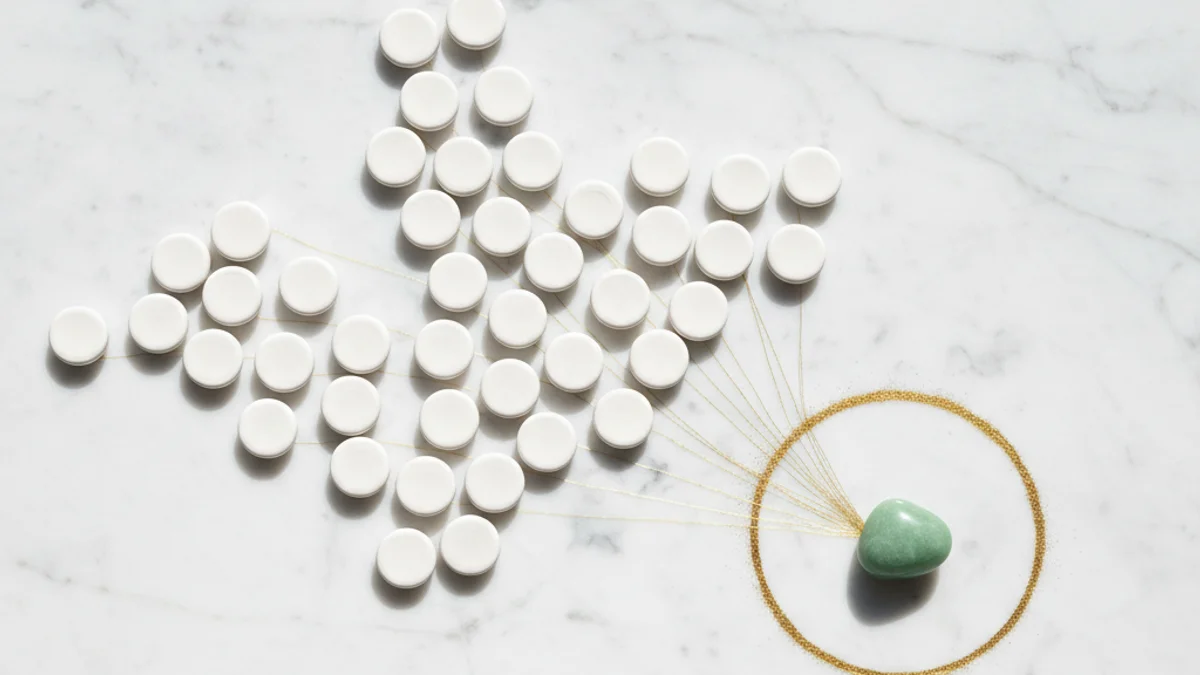 Pedras brancas dispersas conectadas por fios dourados a uma pedra verde central.