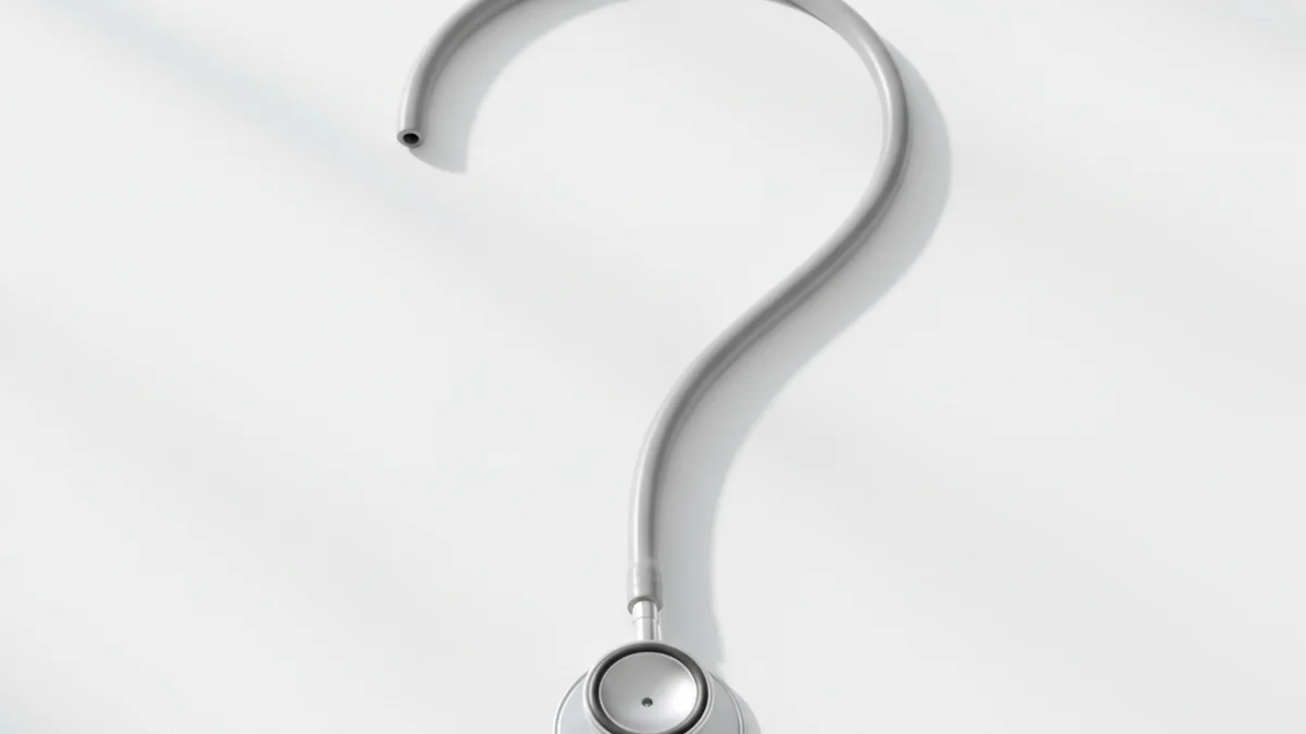 Estetoscópio prata disposto em formato de ponto de interrogação sobre superfície branca clínica.