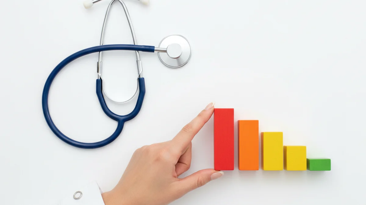 Estetoscópio e blocos de madeira em sequência decrescente sobre superfície branca clínica.